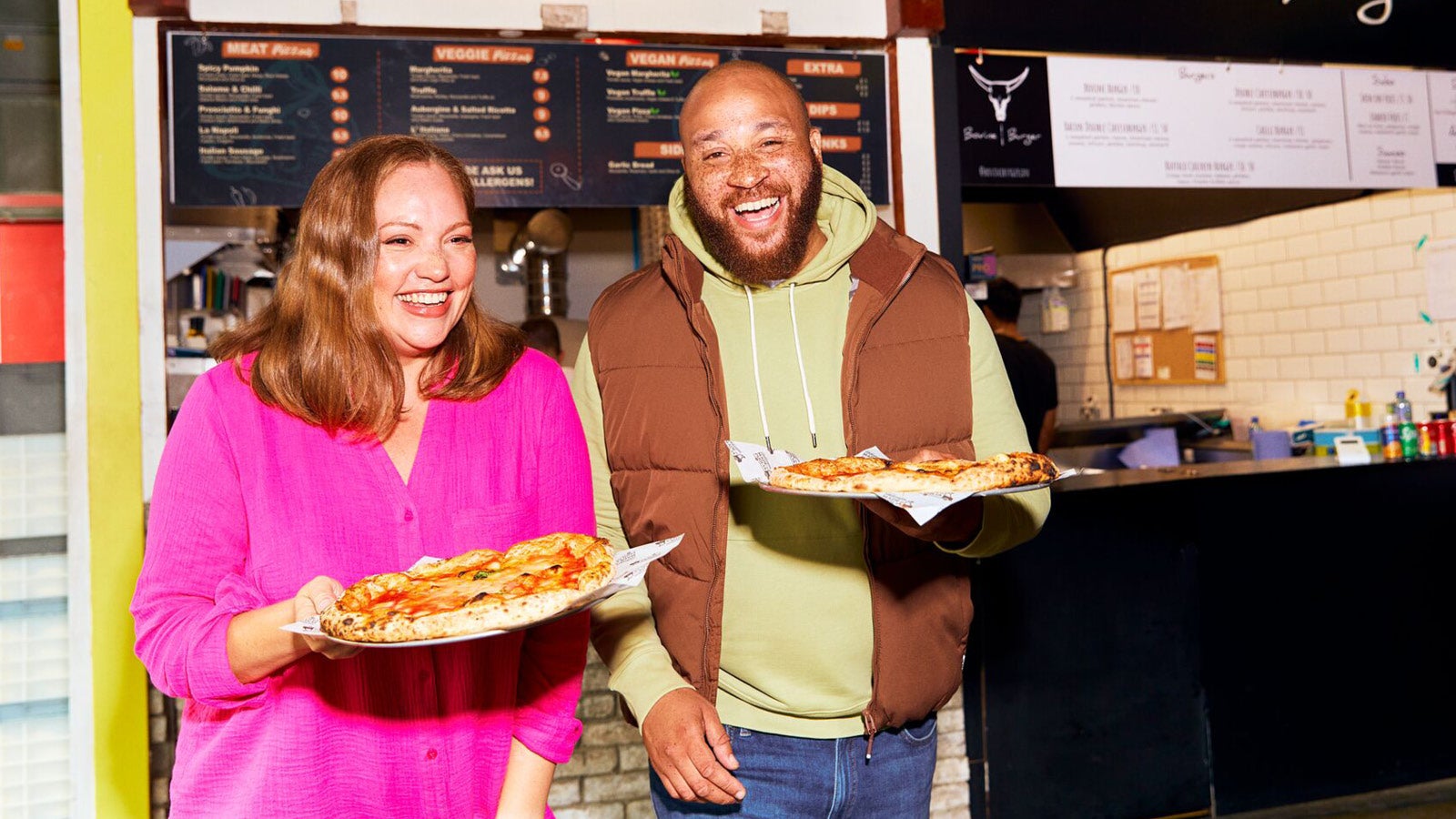 a man and woman holding plates of pizza