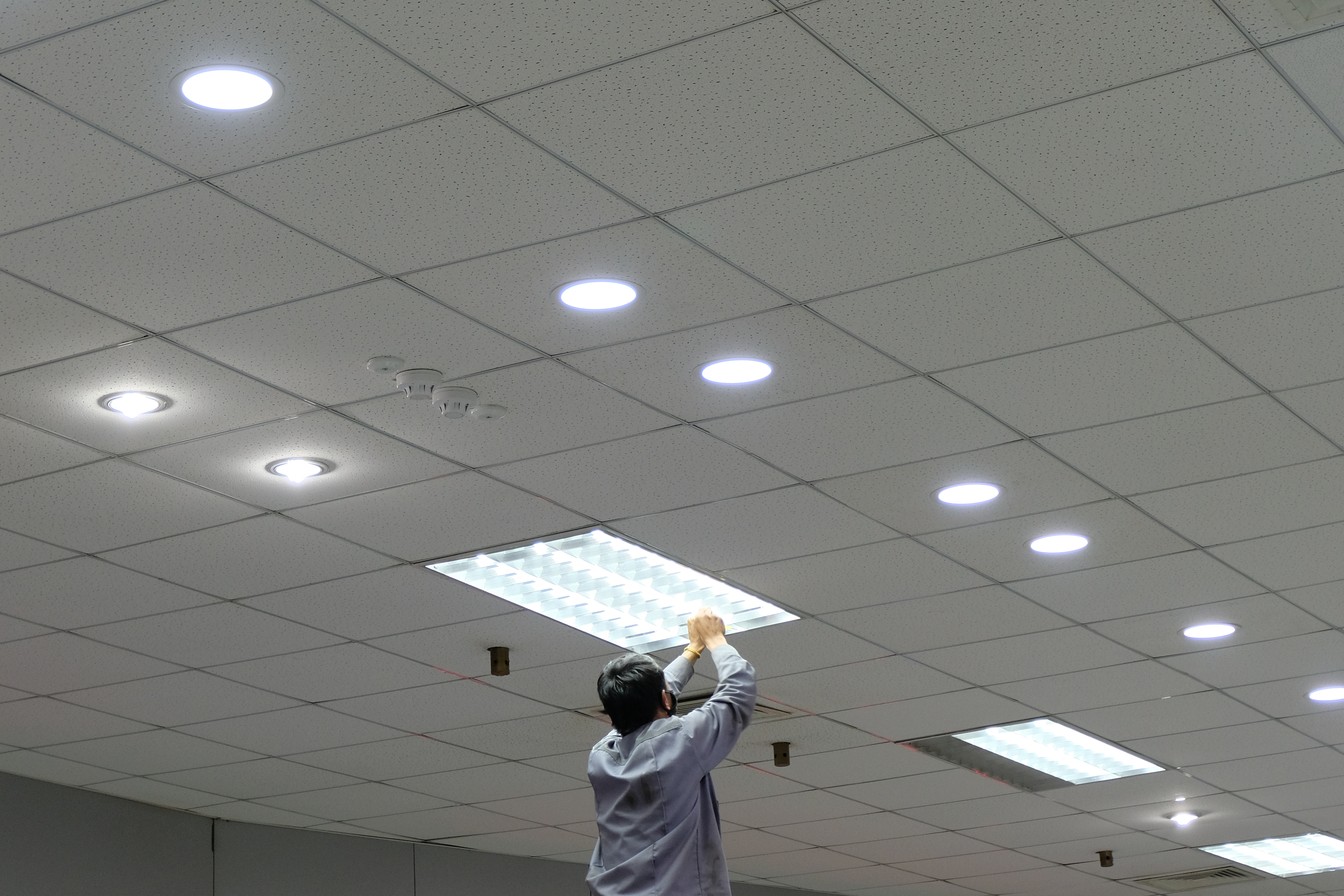 a man fixing a light on the ceiling
