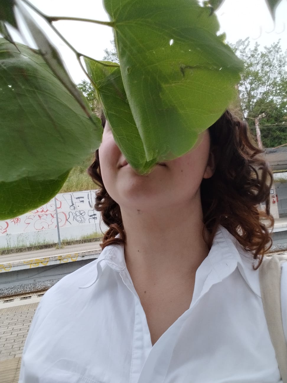 a woman holding a leaf over her face