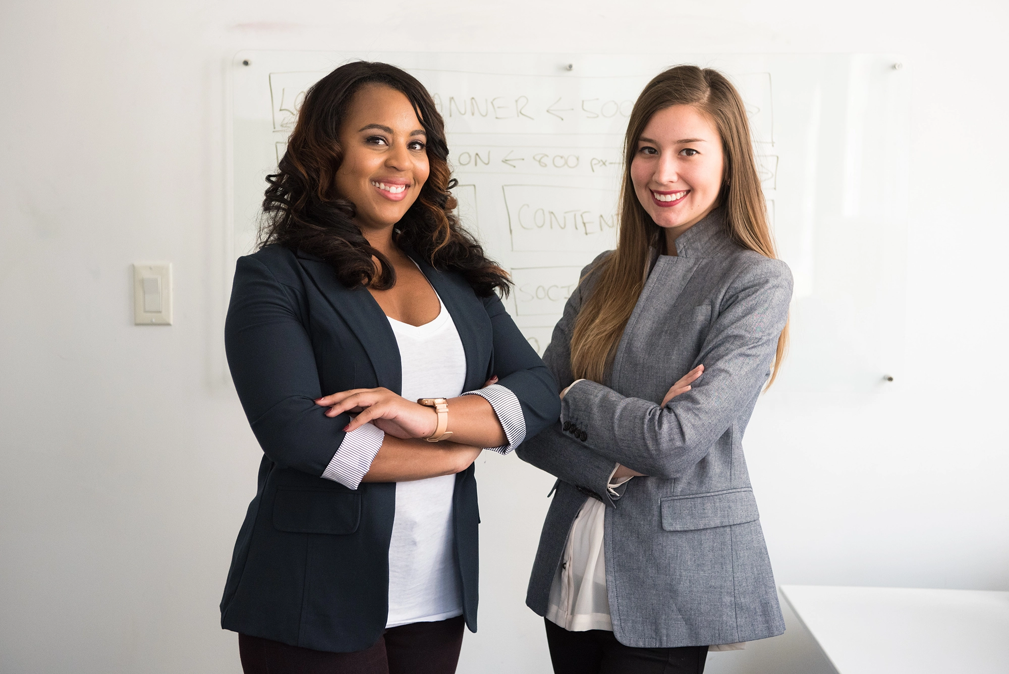 a couple of women standing in front of a whiteboard