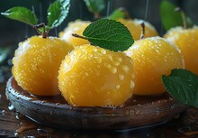 a group of yellow apples with leaves on a wooden plate