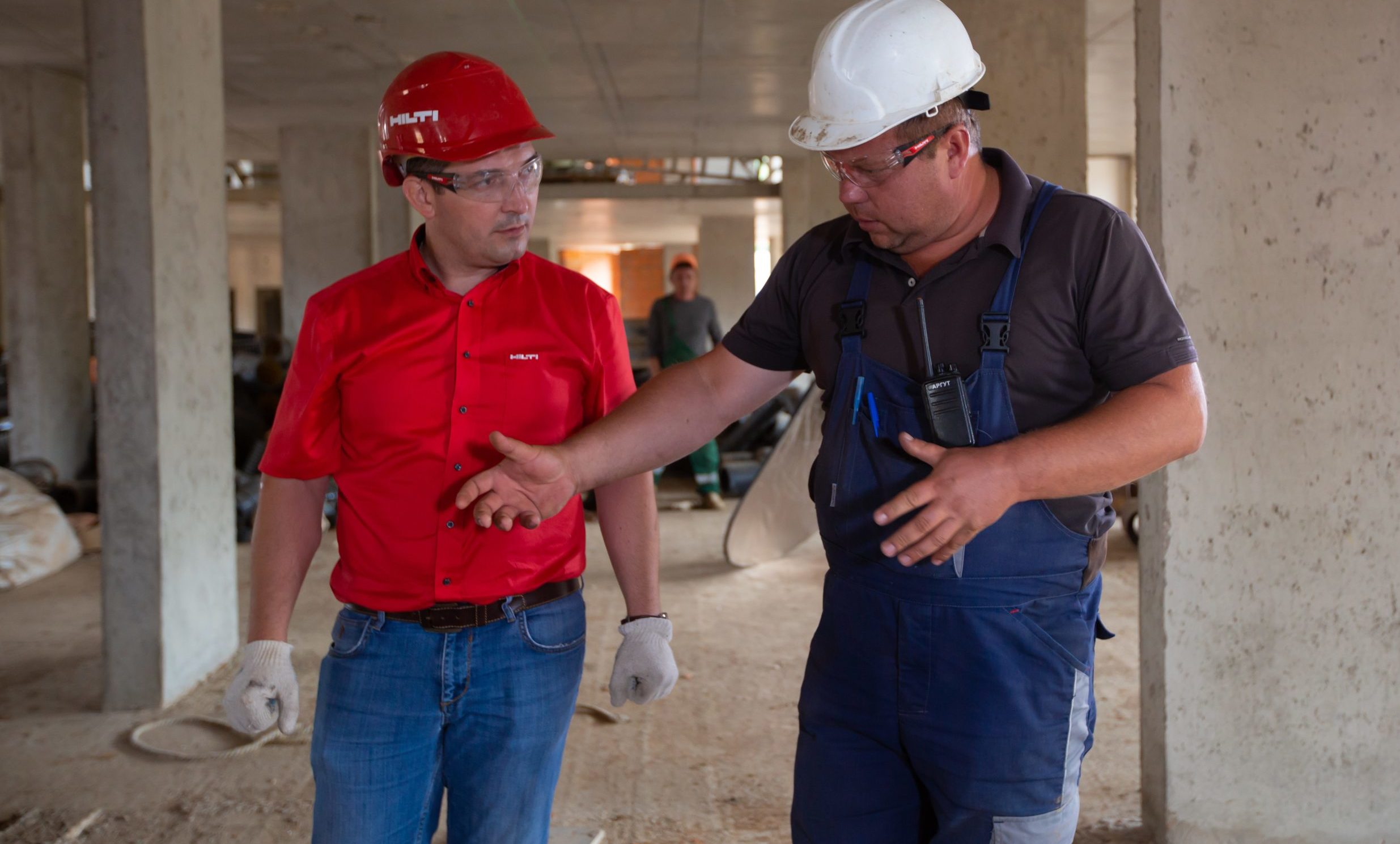 a man in hardhat shaking hands with another man in a construction site