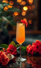 a glass of orange liquid with a flower on top