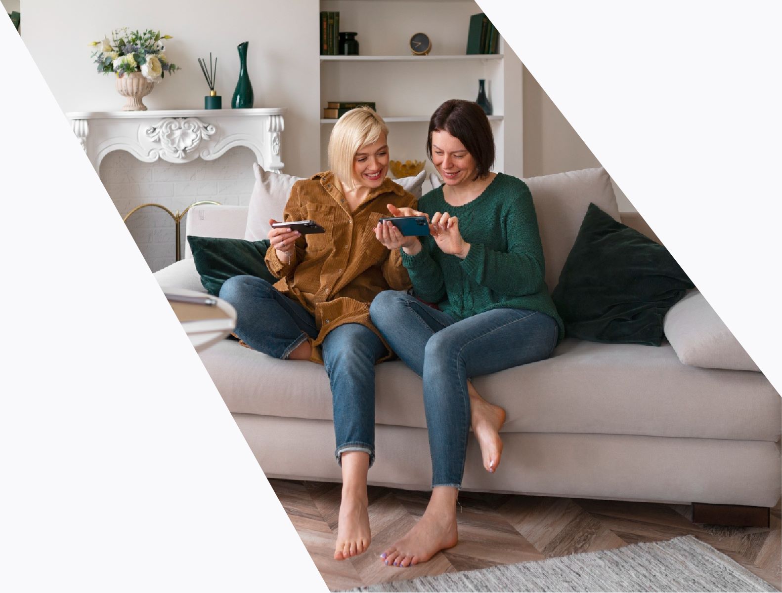 two women sitting on a couch looking at a phone