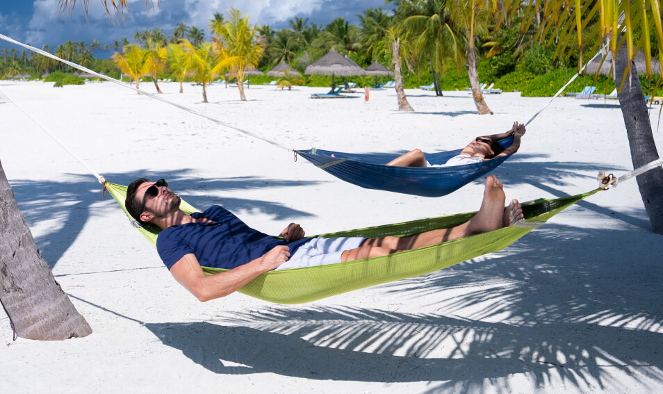 a man and woman lying in hammocks on a beach