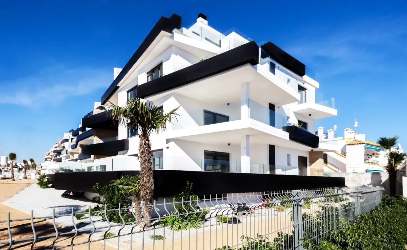 a building with a fence and palm trees