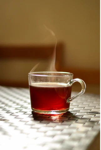 a glass cup of coffee with steam coming out of it