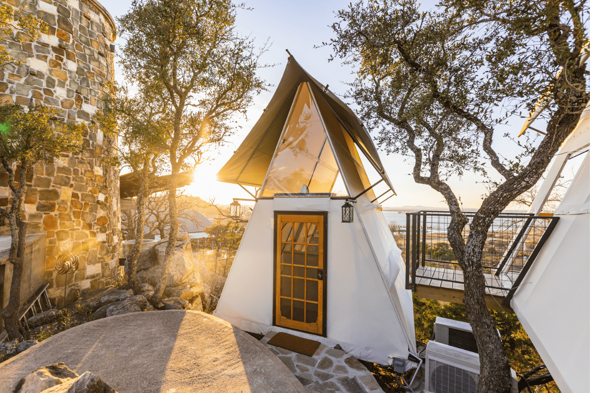 a small white tent with a glass door and a balcony