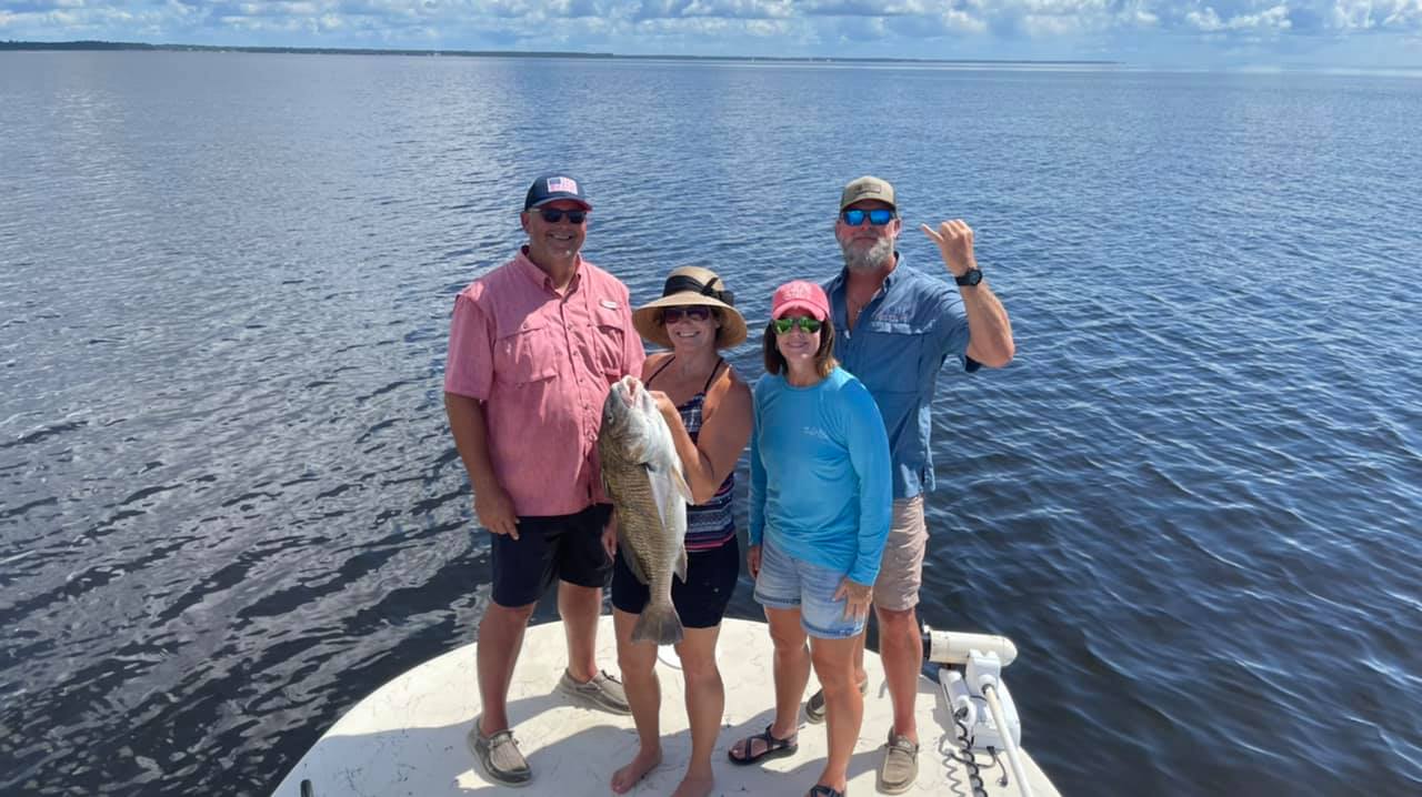 a group of people holding a fish on a boat