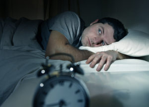 a man lying in bed with an alarm clock