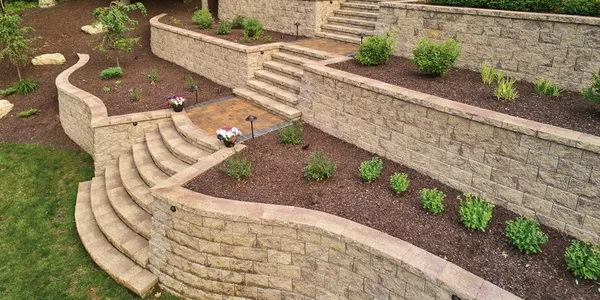 a stone retaining wall with steps and plants