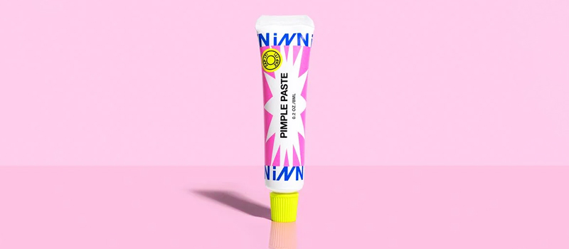a tube of paste on a pink background