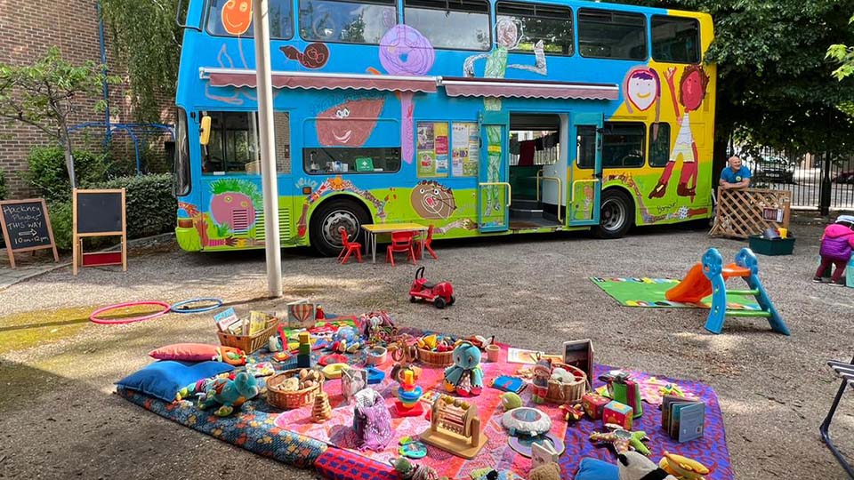 a picnic blanket and toys on a blanket outside of a bus