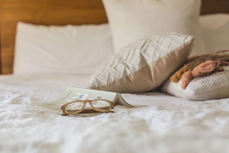 a book and glasses on a bed