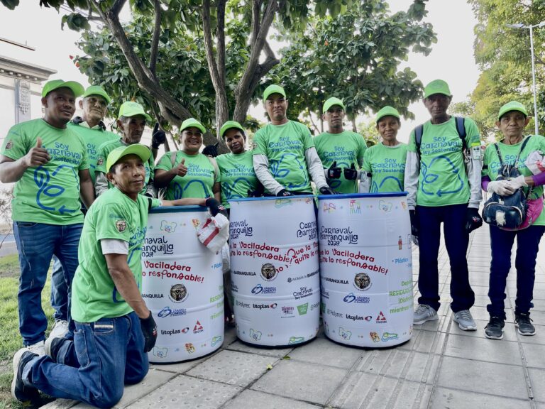 a group of people wearing green shirts and standing next to large barrels