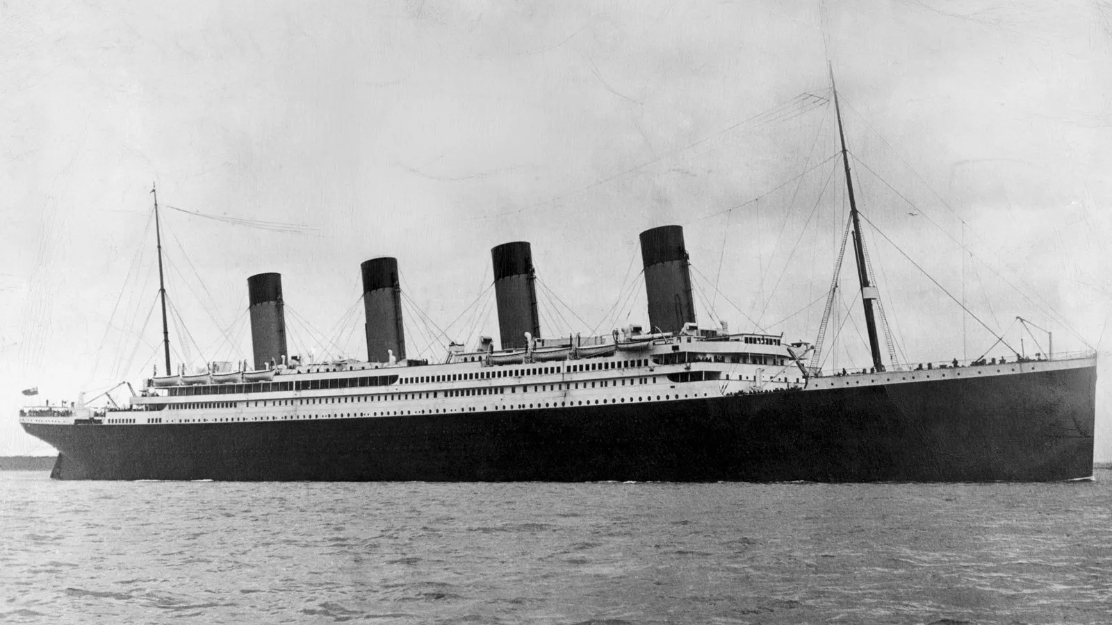 a large ship in the water with RMS Queen Mary in the background