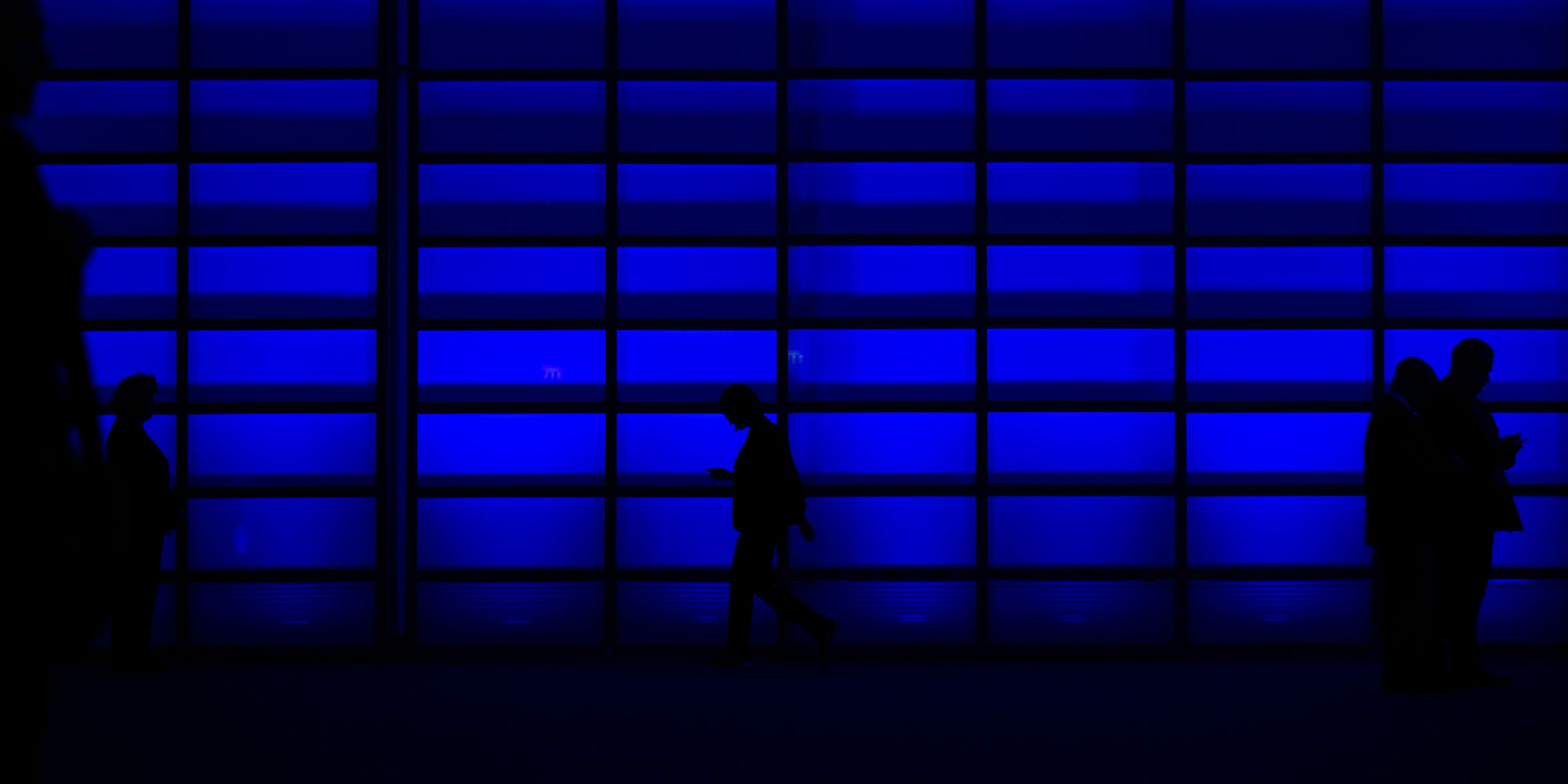 a silhouette of a person walking in front of a blue wall