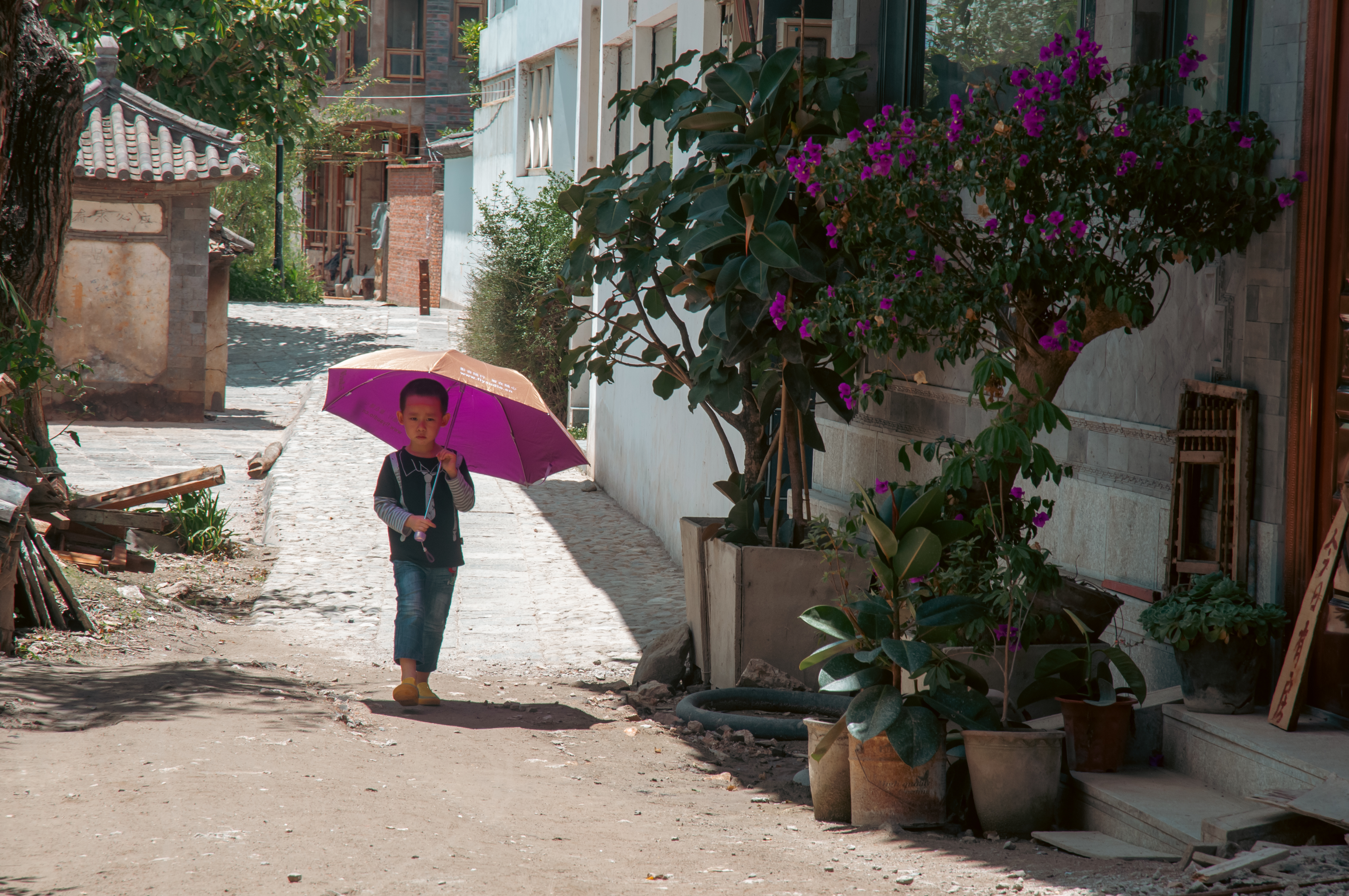 a boy holding an umbrella on a street
