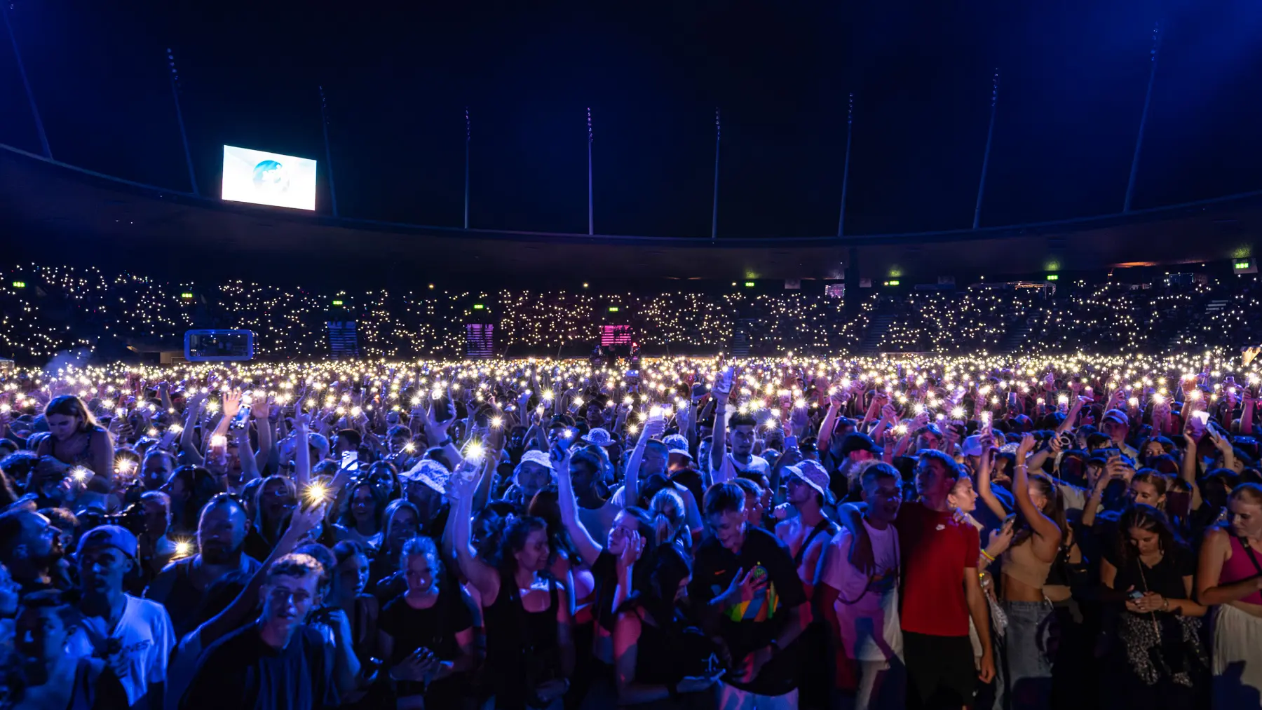 a large crowd of people in a stadium with lights