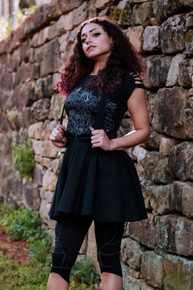 a woman in black dress and black pants standing in front of a stone wall
