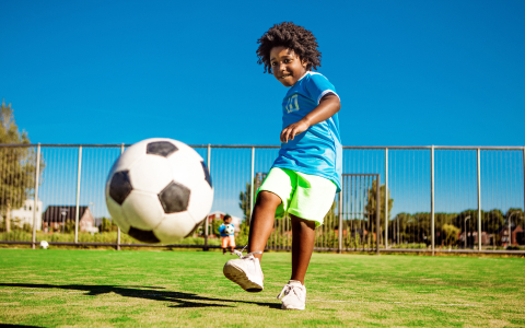 a child kicking a football ball