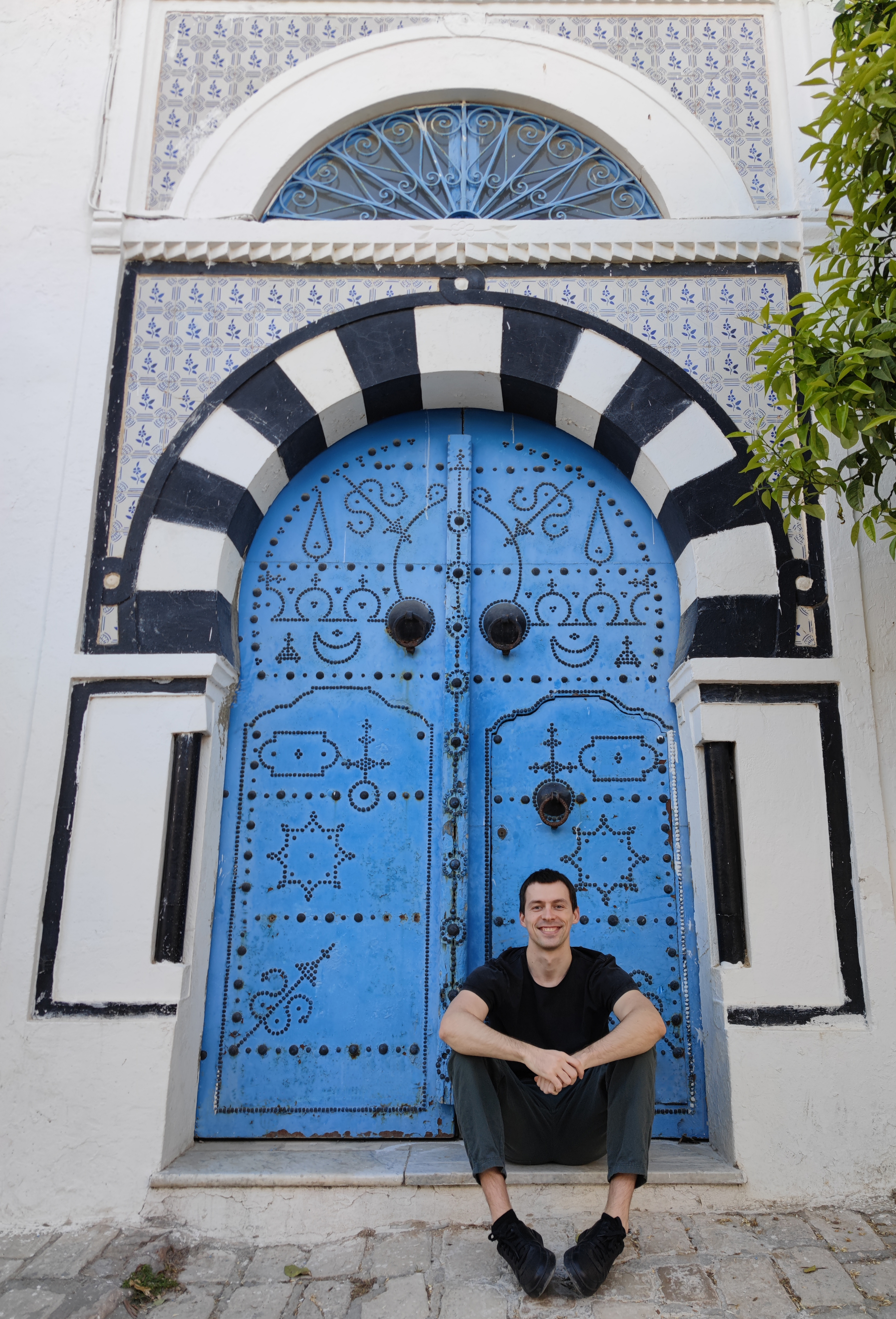 a man sitting in front of a blue and white door