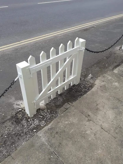 a white gate on a sidewalk