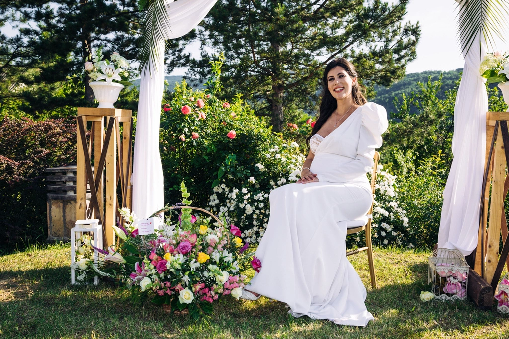 a woman in a white dress sitting in a chair with flowers