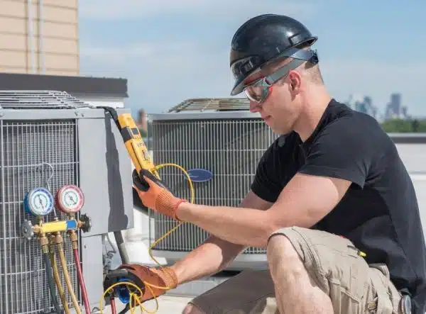 a man wearing a helmet and gloves working on a air conditioner