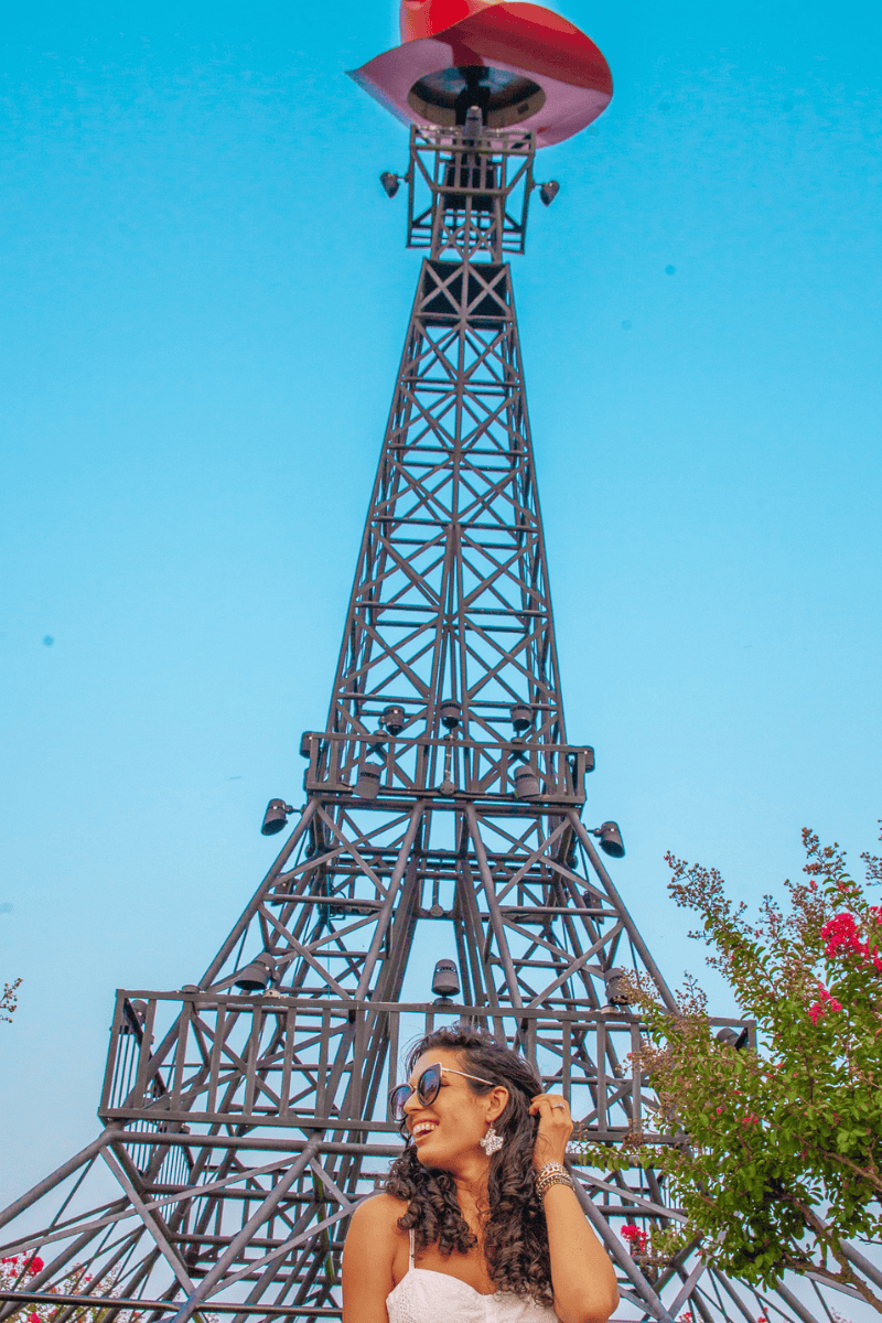a woman taking a selfie in front of a metal tower
