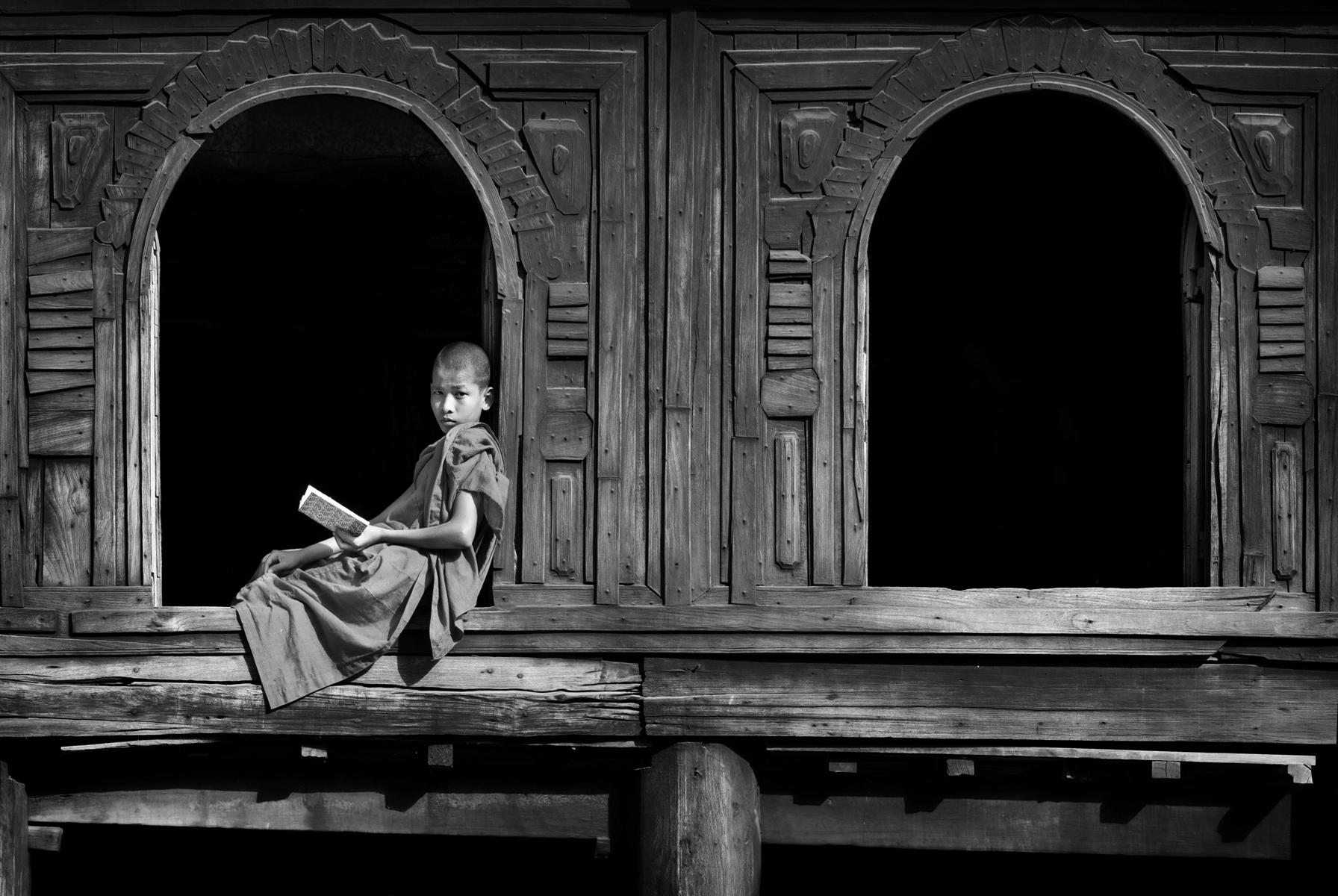 a child sitting on a ledge reading a book