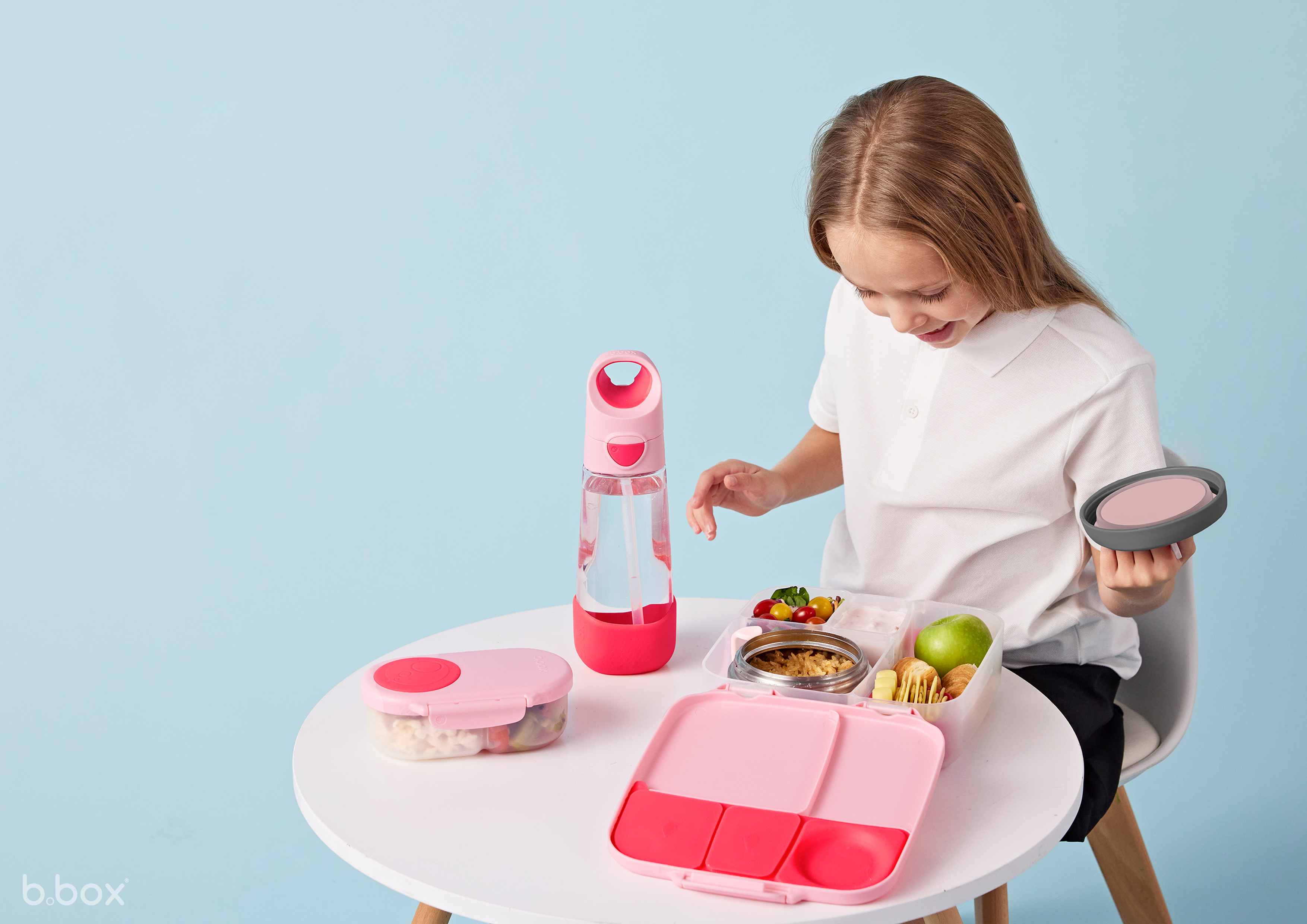 a girl sitting at a table with food