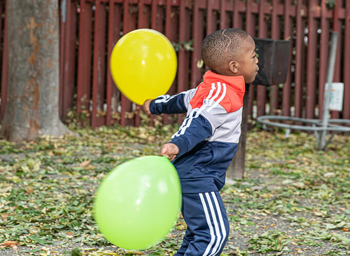 a boy holding two balloons