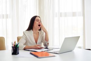 a woman yawning at a desk