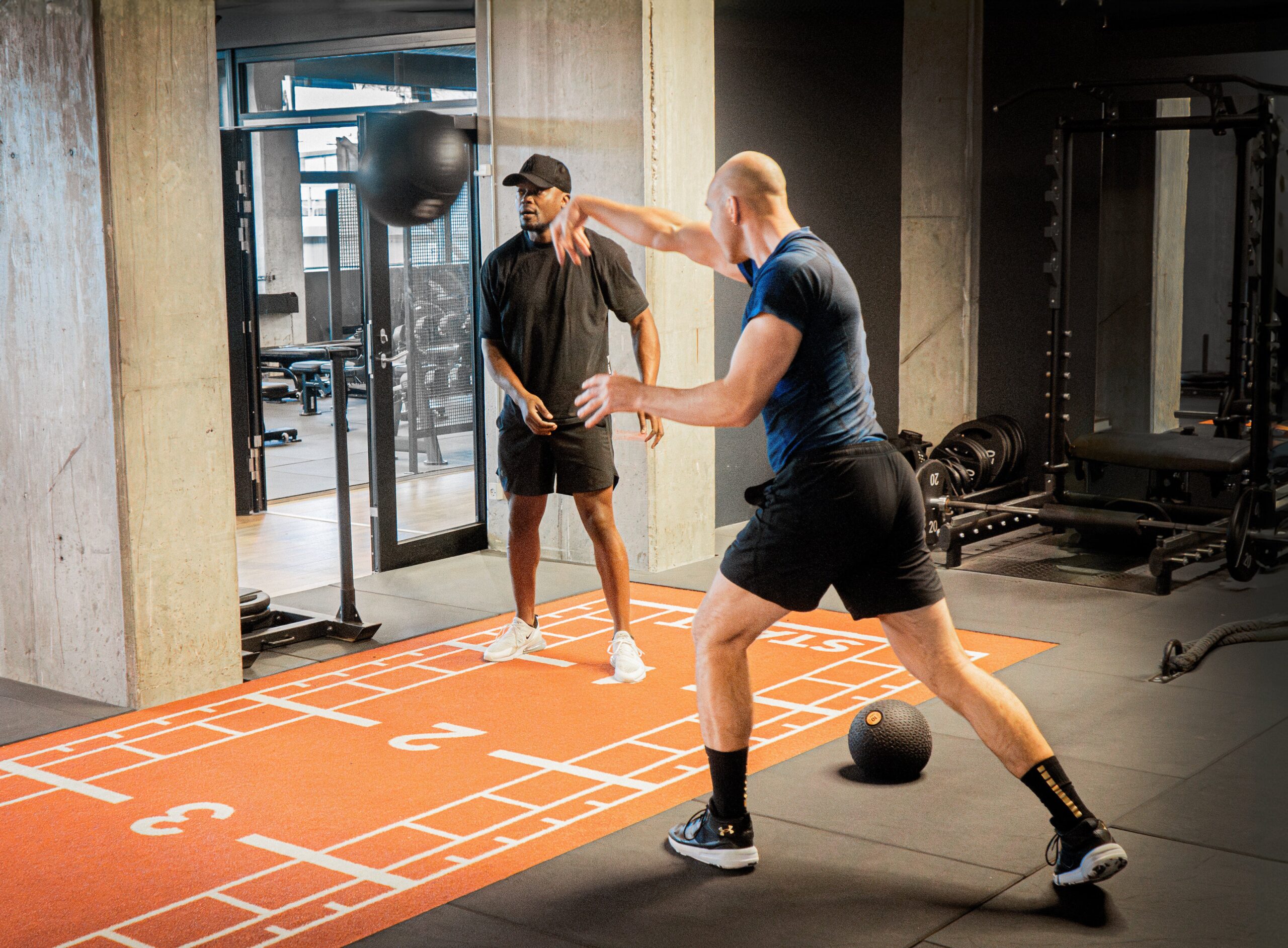 a man hitting a ball with another man in a gym