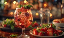 a glass of drink with ice and strawberries on a plate