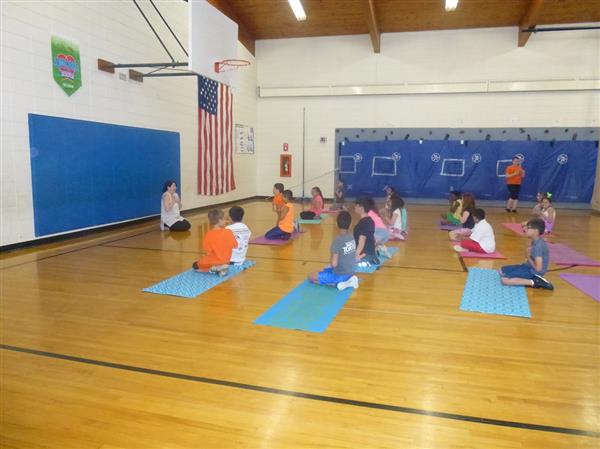 a group of kids sitting on mats in a gym