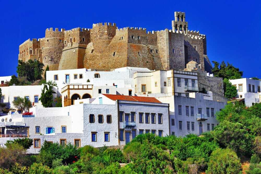 a castle on top of a white building with Patmos in the background