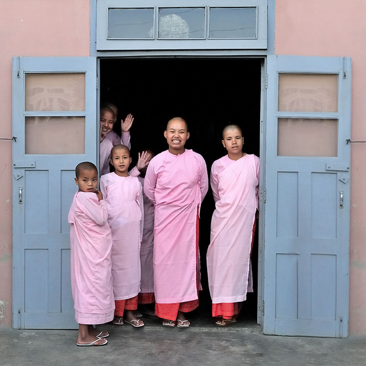 a group of people in pink robes standing in a doorway