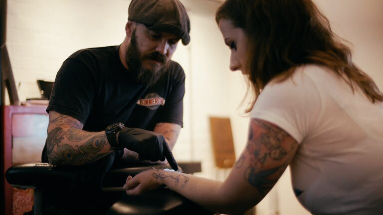 a man getting a tattoo on a woman's arm