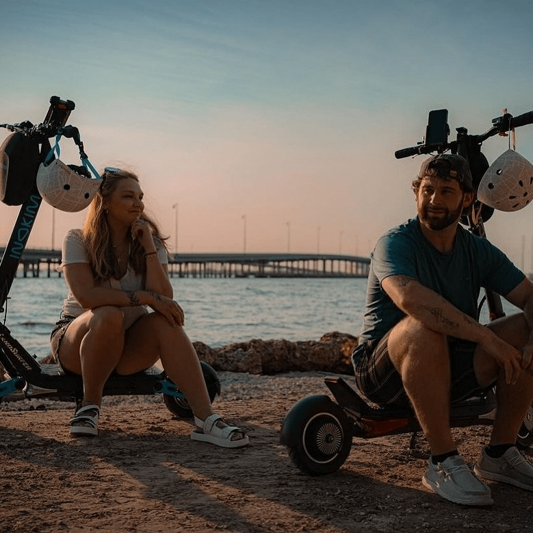 a man and woman sitting on scooters next to water