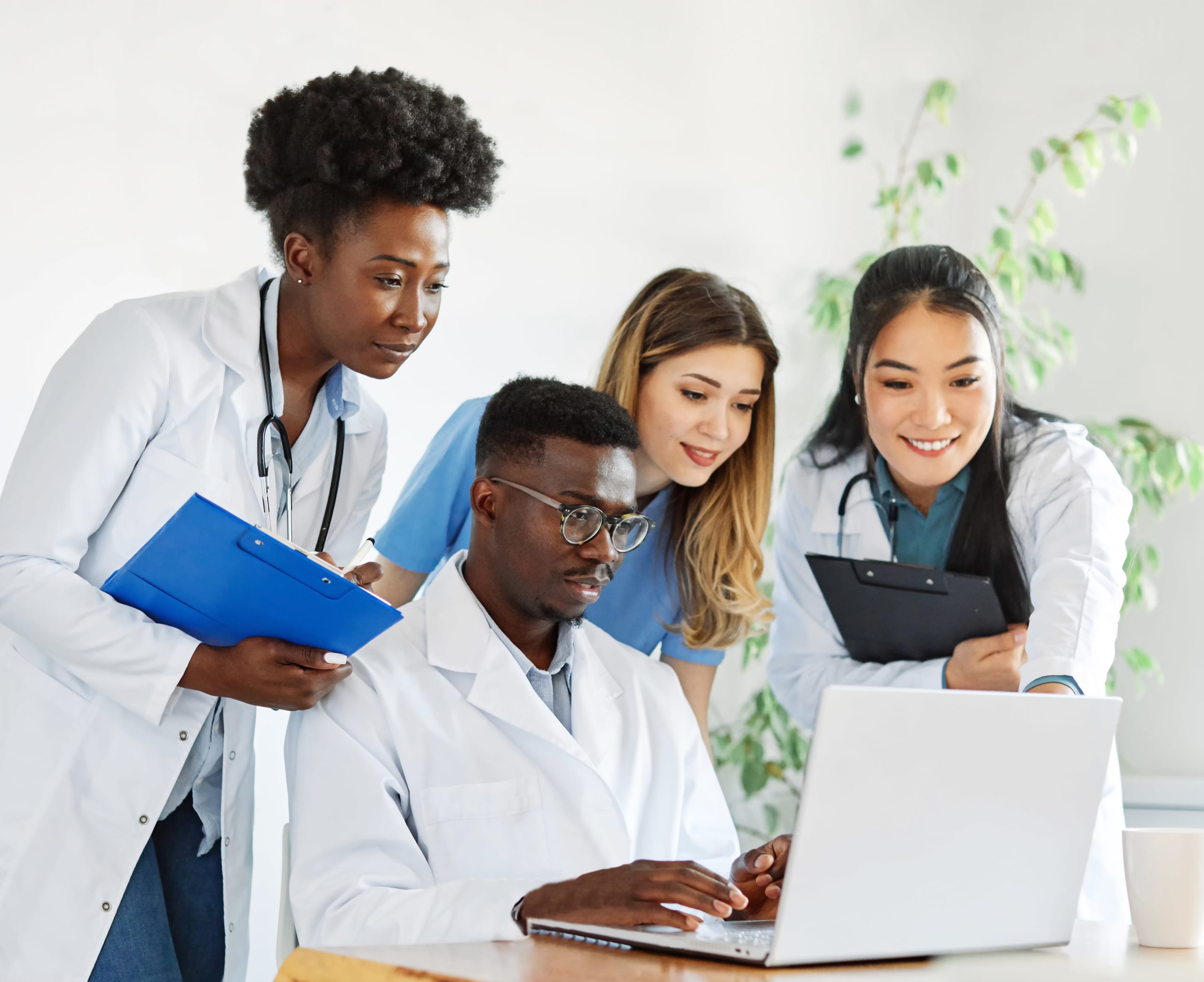 a group of people in white coats looking at a laptop