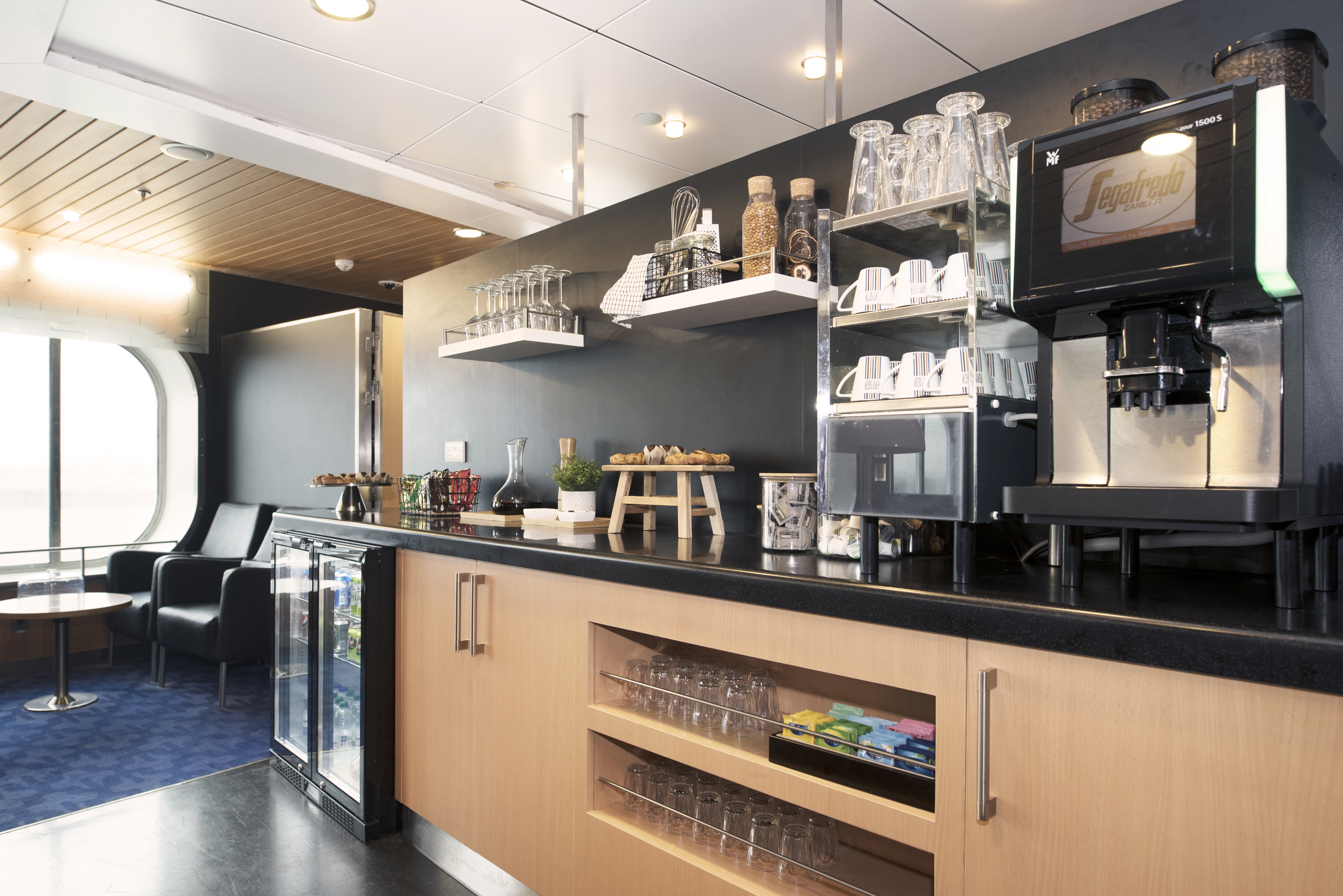 a coffee bar with shelves and glasses on the wall