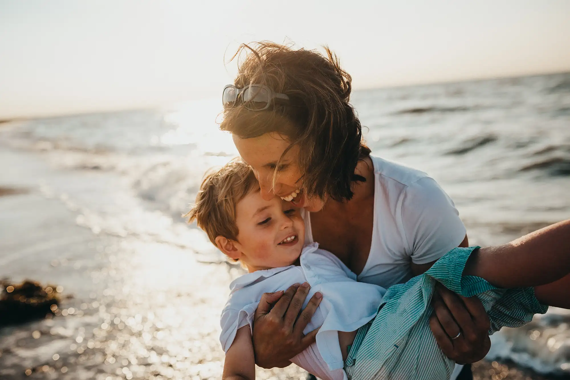 a woman holding a child on a beach