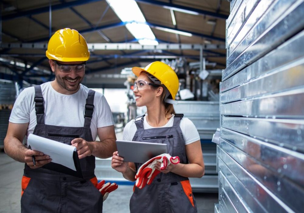 a man and woman wearing hardhats and holding papers