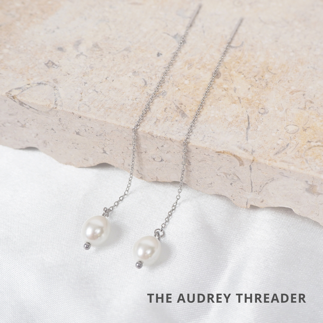 a pair of pearl necklaces on a stone surface