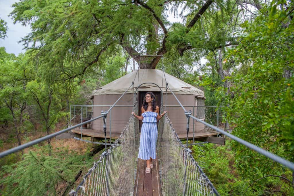 a woman standing on a bridge over a tree house