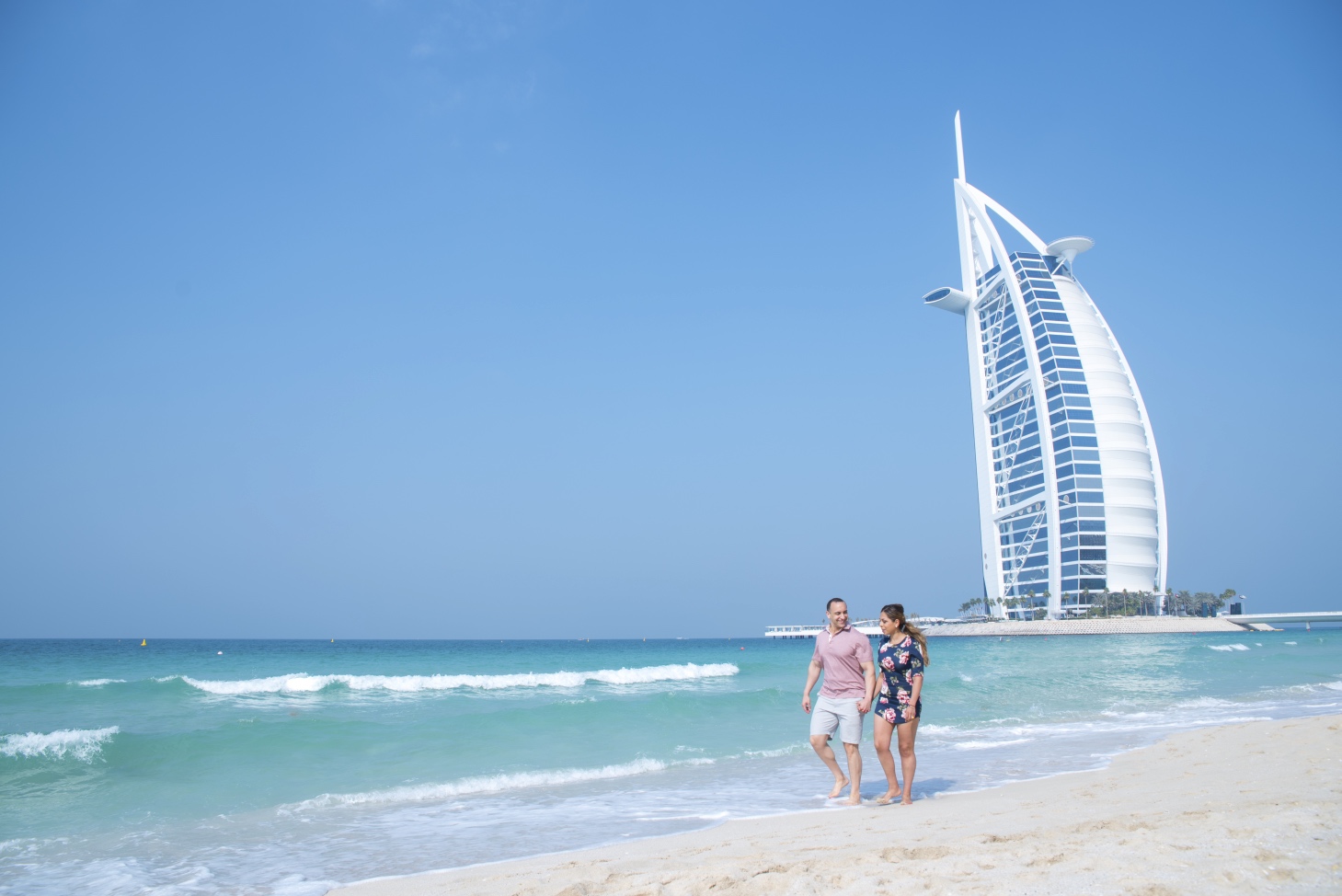 a man and woman standing on a beach with a tall building in the background