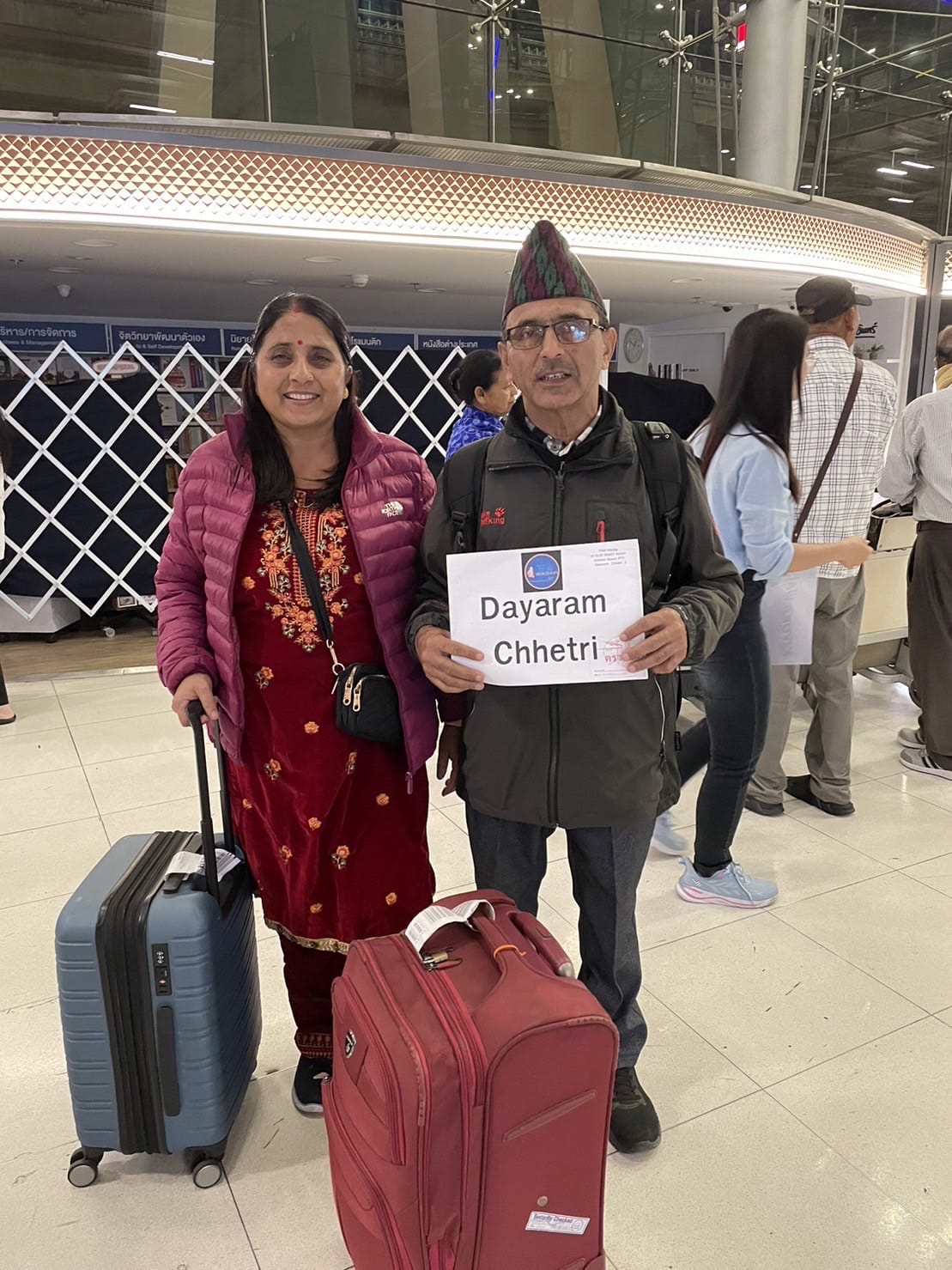 a man and woman holding a sign and luggage