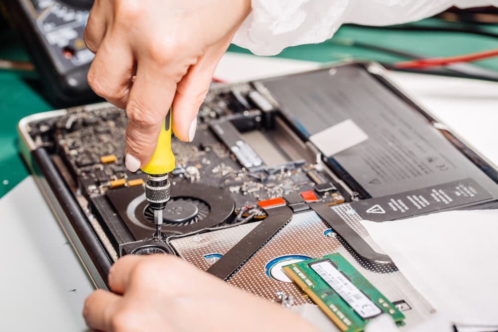 a person using a screwdriver to fix a computer